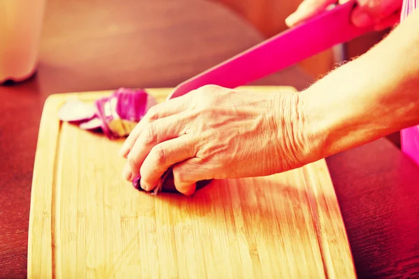Mulher cortar cebola vermelha na placa de corte — Fotografia de Stock