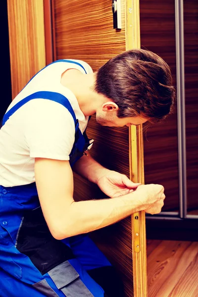 Young man fixing the door with screwdriver — Stock Photo, Image