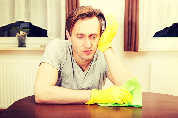 Tired man in yellow gloves sitting behind the desk — Stock Photo, Image