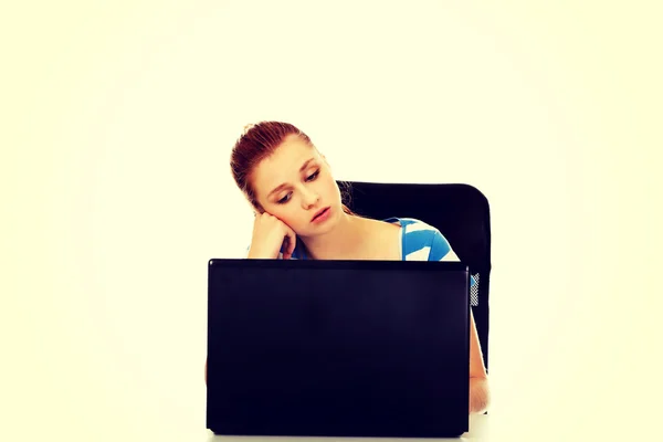 Masanın arkasında oturan dizüstü bilgisayar ile yorgun genç kadın — Stok fotoğraf