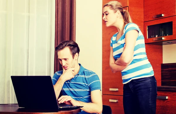 Man watching something on laptop, his wife trying to look what he doing — Stock Photo, Image