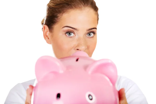 Young beautiful female doctor or nurse holding a piggybank — Stock Photo, Image