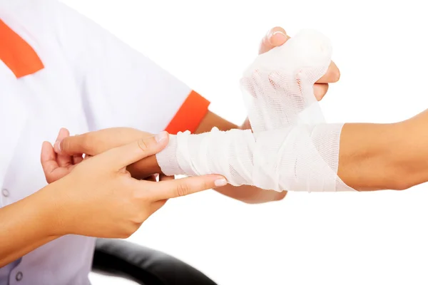 Young smile woman doctor bandaging female hand — Stock Photo, Image