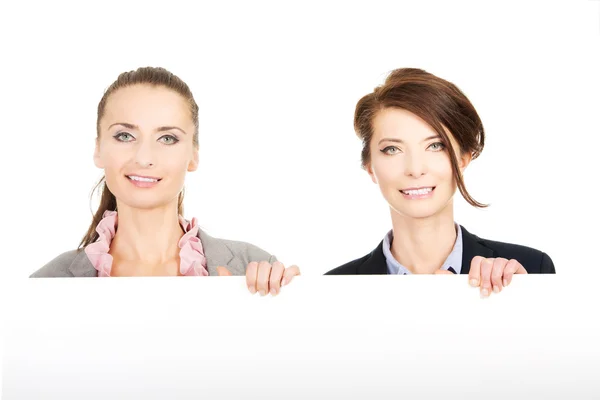 Duas mulheres de negócios carregando uma grande placa branca . — Fotografia de Stock