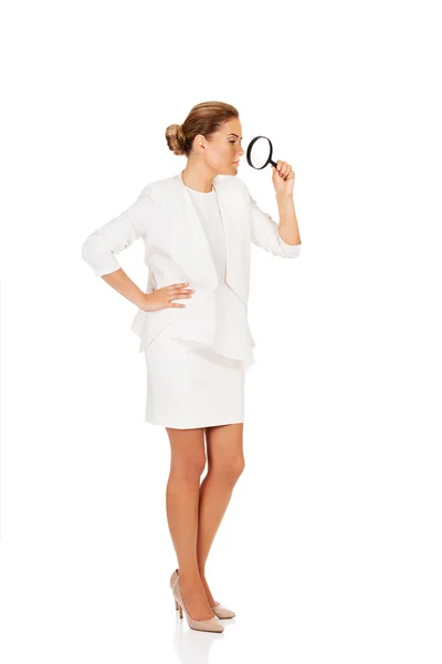 Young attractive businesswoman looking into a magnifying glass — Stock Photo, Image