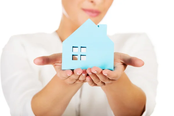 Бизнесмен, держащая в руках голубой бумажный дом — стоковое фото