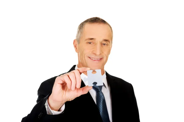 Smart businessman holding a puzzle — Stock Photo, Image