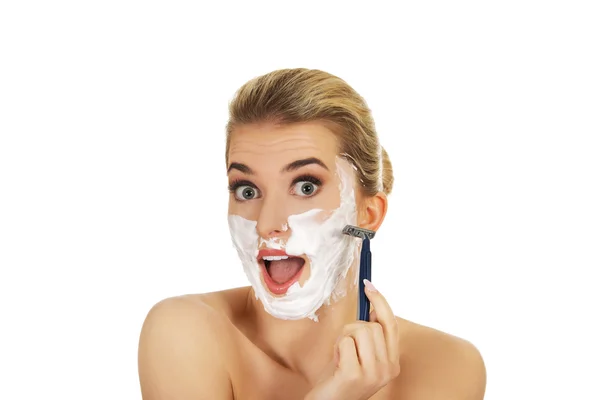 Young shocked woman shaving her face with a razor — Stock Photo, Image