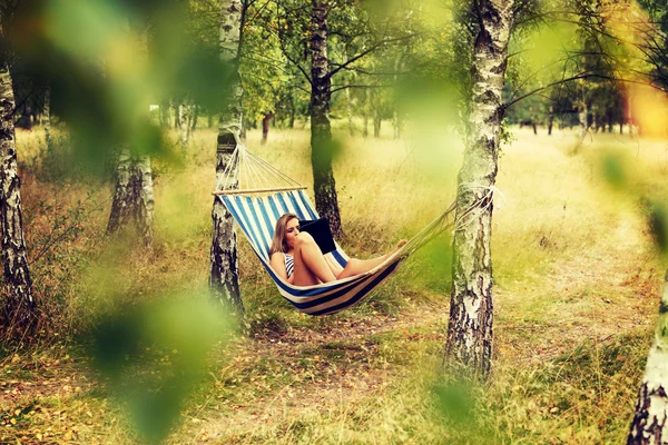 Ung kvinna med tablett på hängmattan — Stockfoto