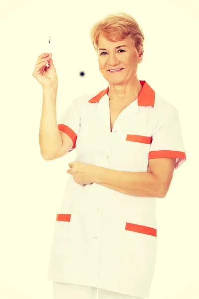 Улыбайтесь, пожилая женщина врач или медсестра держит шприц — стоковое фото