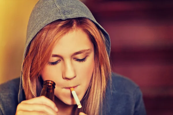 Teenage woman drinking beer and smoking cigarette — Stock Photo, Image