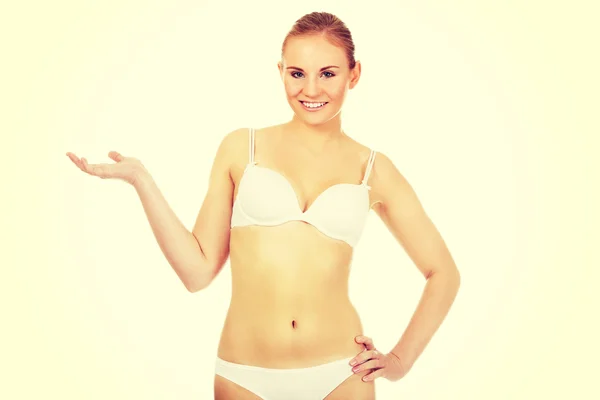 Happy woman in white lingerie presenting something on open palm — Stock Photo, Image