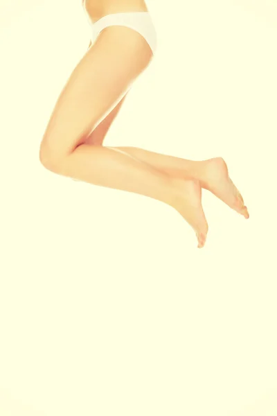 Pernas e parte inferior de mulher saltando em calcinha branca — Fotografia de Stock