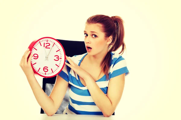 Young shocked teenage woman looking at clock — Stock Photo, Image