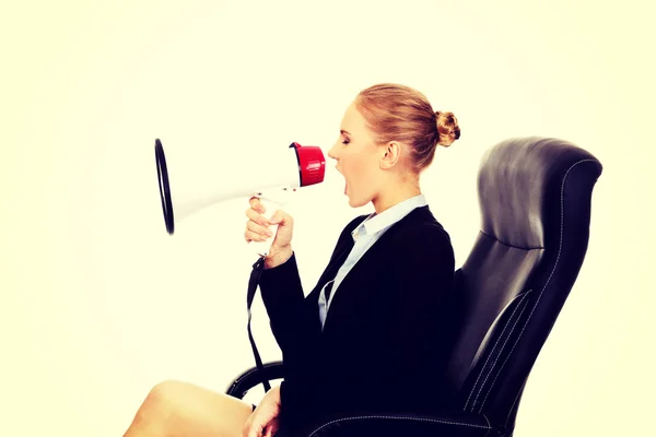 Mulher de negócios sentada em poltrona e gritando através de um megafone — Fotografia de Stock