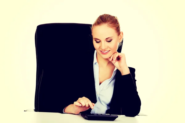 Glimlach zakenvrouw met behulp van rekenmachine achter het bureau — Stockfoto