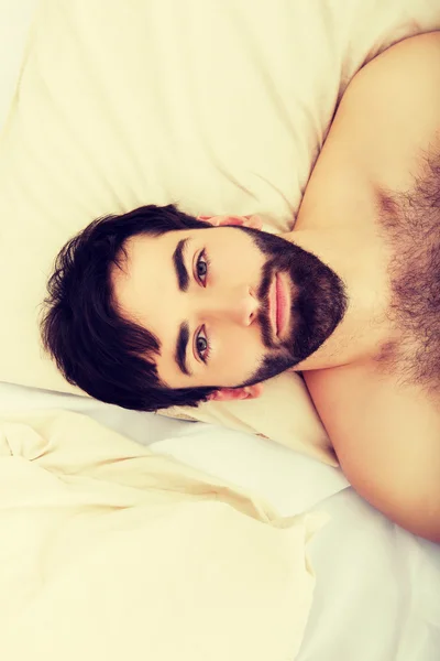 Junger muskulöser Mann liegt im Bett. — Stockfoto