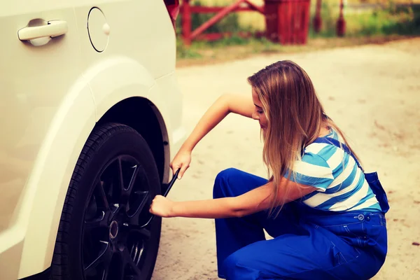 Female mechanic changing tire with wheel wrench — Stock Photo, Image