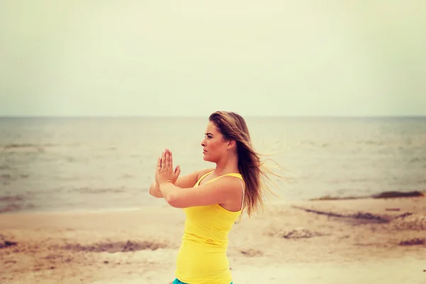 Jovem mulher fazendo exercícios de Yoga na praia — Fotografia de Stock