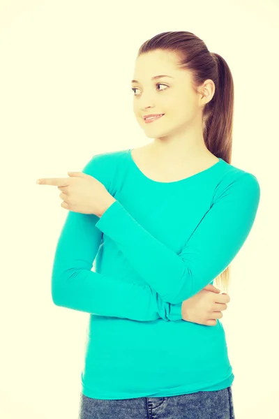 Smiling young woman pointing aside. — Stock Photo, Image