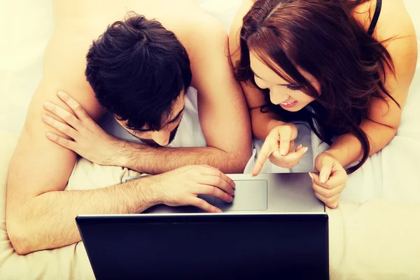 Pareja feliz en el ordenador portátil en el dormitorio . —  Fotos de Stock