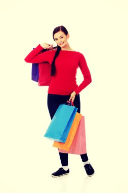 Alışveriş torbaları tutan genç mutlu gülümseyen kadın