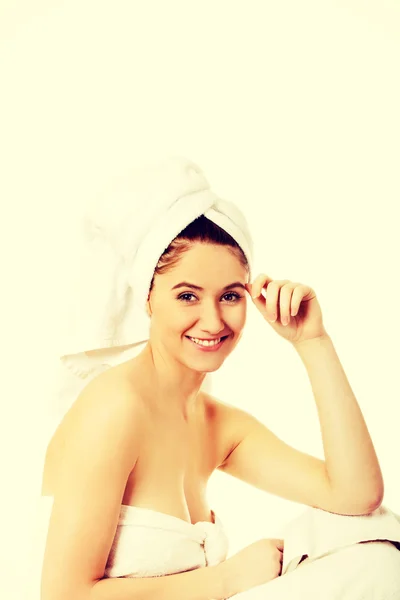 Mladý úsměv žena zabalené ručníky sedí — Stock fotografie