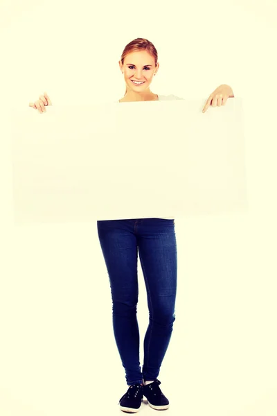 Smiling young woman pointing for empty banner — Stock Photo, Image