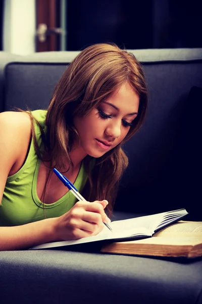 Mujer joven aprendiendo a examinar en un sofá . — Foto de Stock