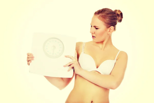 Slim shocked woman holding a weight scale — Stock Photo, Image