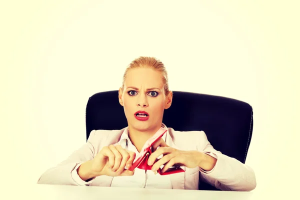 Mujer de negocios preocupada sentada detrás del escritorio con la cartera vacía —  Fotos de Stock