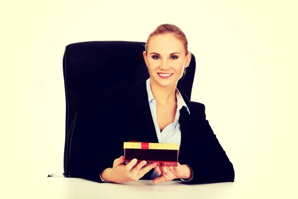 Sourire femme d'affaires avec boîte cadeau assis derrière le bureau — Photo