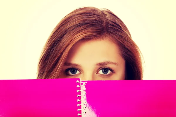 Teenage woman hiding her face behind a notebook — Stock Photo, Image