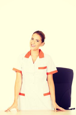 Masanın arkasında kadın doktor veya hemşire duran genç gülümsemek