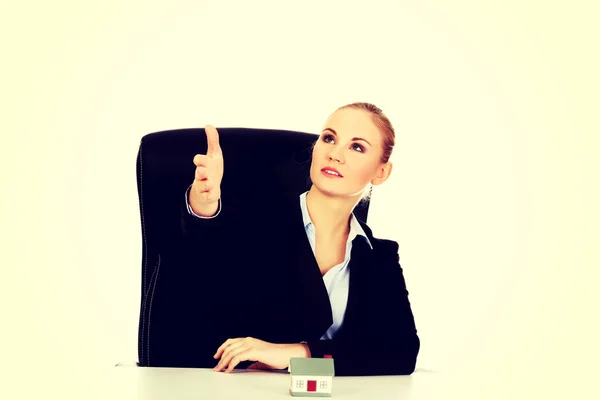 Geschäftsfrau mit offener Hand zum Händedruck und Hausmodell auf dem Schreibtisch — Stockfoto