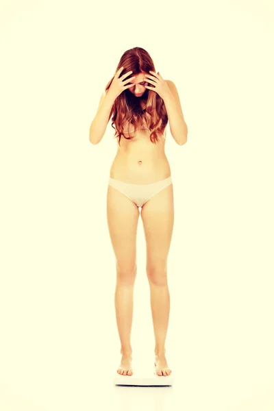 Молодая шокированная женщина в нижнем белье стоящая на весах — стоковое фото