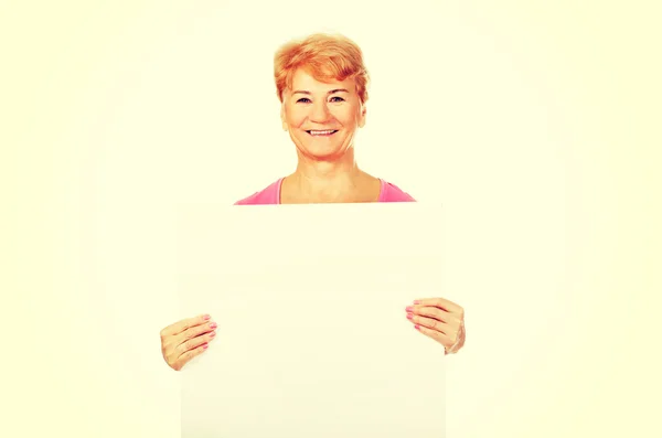 Sorrindo mulher idosa segurando banner vazio — Fotografia de Stock