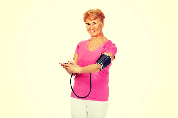 Mujer mayor sonriente midiendo la presión arterial — Foto de Stock