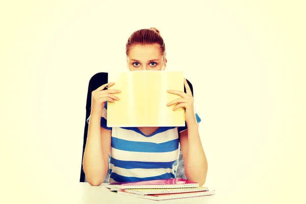 Teenagerin versteckt ihr Gesicht hinter einem Notizbuch — Stockfoto