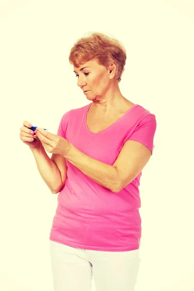 Worried senior woman looking for thermometer — Stock Photo, Image