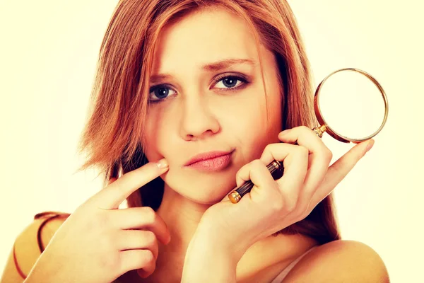 Thinking teenage woman holding magnifying glass — Stock Photo, Image