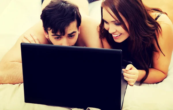 Pareja feliz en el ordenador portátil en el dormitorio . — Foto de Stock