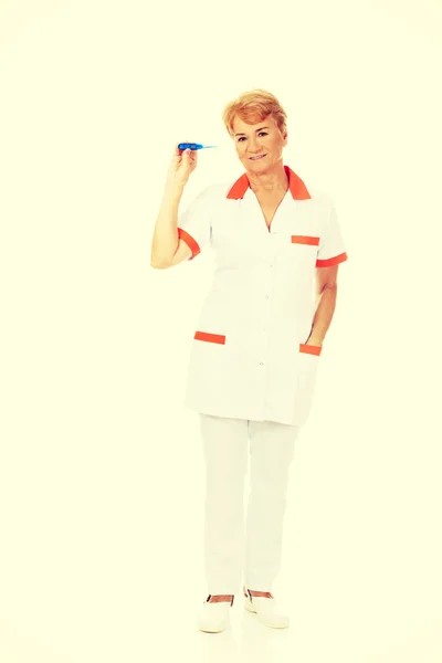 Улыбайтесь, пожилая женщина врач или медсестра держит термометр — стоковое фото