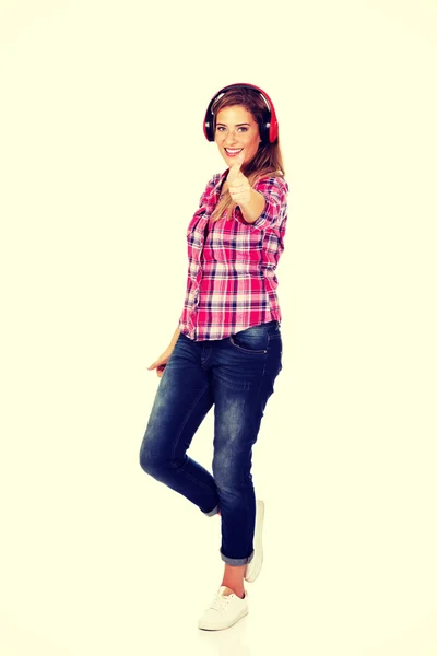 Mujer joven con auriculares rojos escuchando música — Foto de Stock