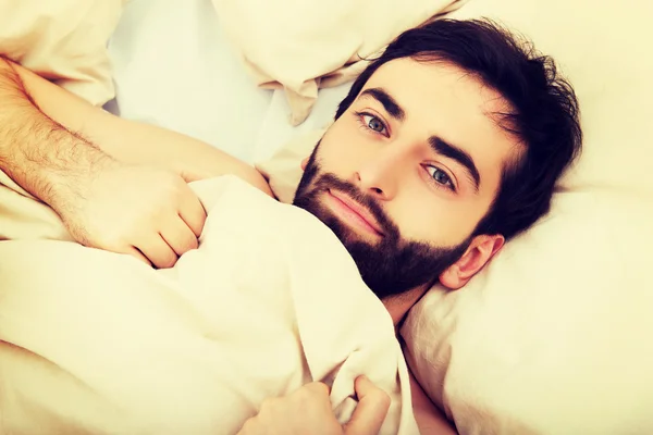 Junger muskulöser Mann liegt im Bett. — Stockfoto