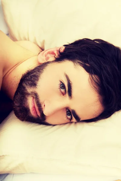 Young muscular man lying in bed. — Stock Photo, Image