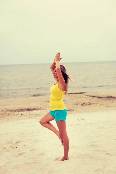 Young woman making yoga exercises on the beach — Stock Photo, Image