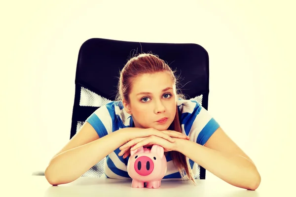 Teenage woman with piggybank on the table — Stock Photo, Image