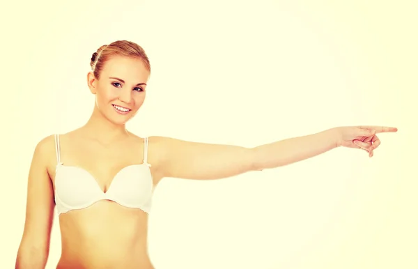 Young woman in white bra pointing for copyspace or something — Stock Photo, Image