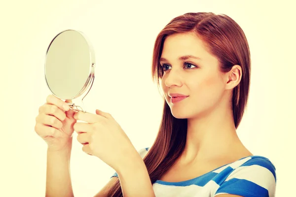 Teenage beautiful woman looking in a mirror — Stock Photo, Image